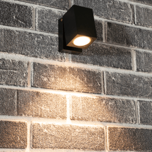 Schwarze, eckige LED Außenwandleuchte mit beweglichem Kopf an einer Backsteinwand.