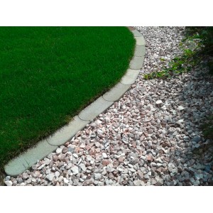 Graue Mähkante aus Beton zwischen Rasen und Kiesweg, flexible Rasenkante für den Garten.