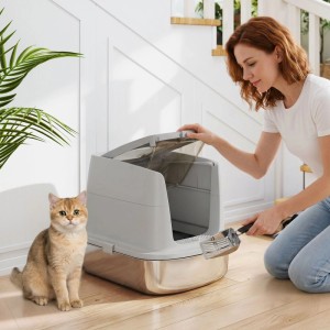 Hellgraue PawHut Katzentoilette aus Edelstahl und Kunststoff. Eine Frau reinigt sie mit Schaufel, eine Katze sitzt daneben.