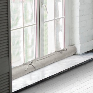 Beautissu Viento Zugluftstopper, 10x120cm, hellgrau, 2er-Set, vor Fenster platziert.