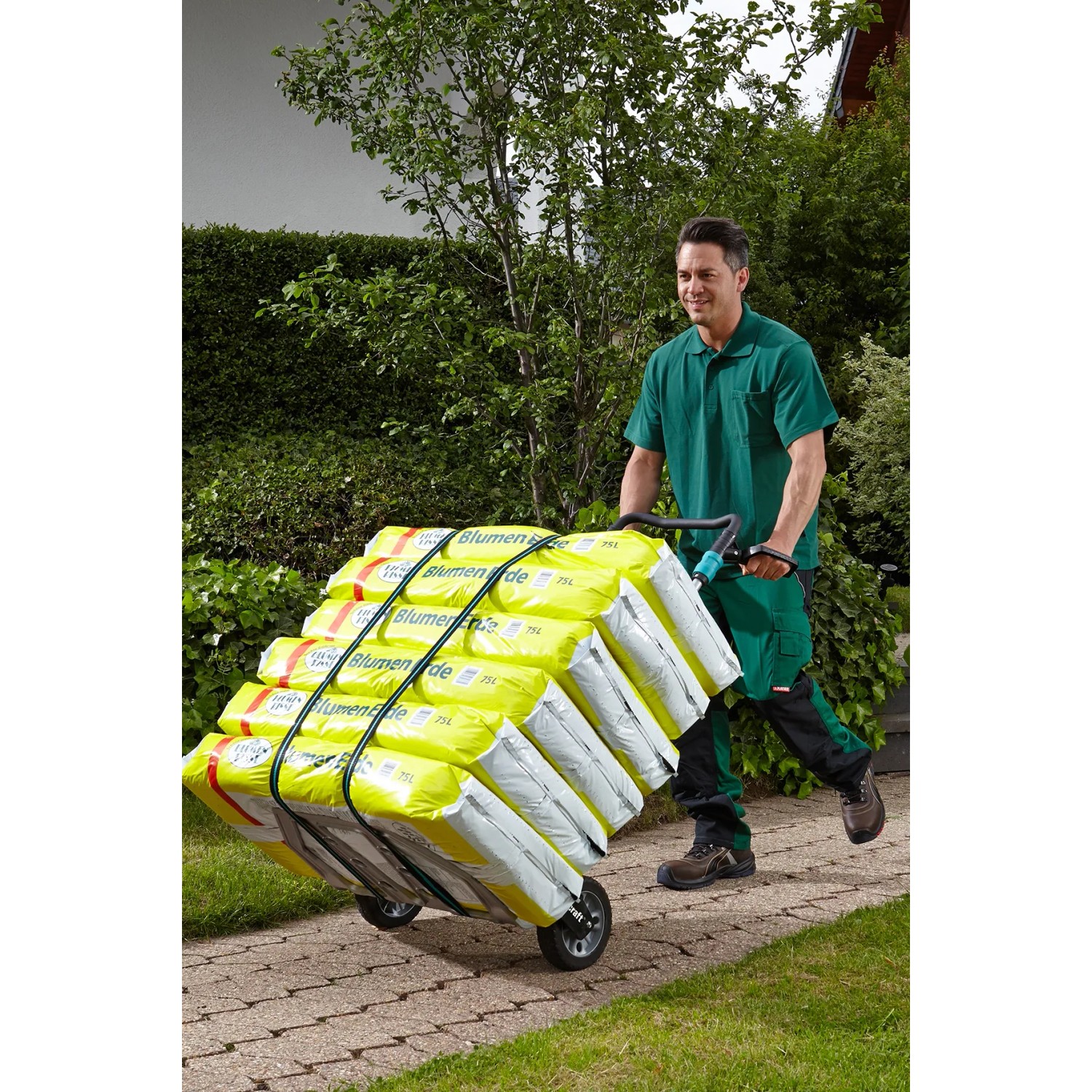 Wolfcraft Sackkarre TS 1500 klappbar mit Mann und beladen mit Blumenerde Säcken.