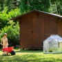 Vitavia Minigewächshaus Merlin im Garten mit Kind und Schubkarre vor Gartenhaus.