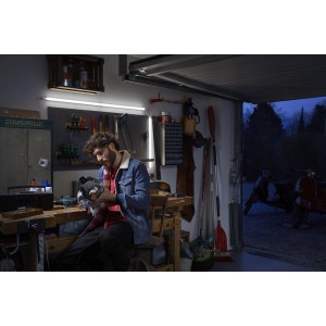 Mann arbeitet unter Ledvance LED-Lichtleiste in Werkstatt. Helles, weißes Licht.