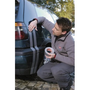 Mann klebt silbernes Tesa Extra Power Gewebeband auf ein Auto. Vielseitig einsetzbares Klebeband.