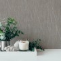 Braune Vliestapete mit Metallic-Glanz und Strukturmuster, kombiniert mit Deko-Elementen.