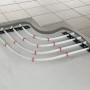 Verlegte, wasserführende Fußbodenheizung (20 m²) mit weißen Rohren und roten Befestigungen unter Fliesen.