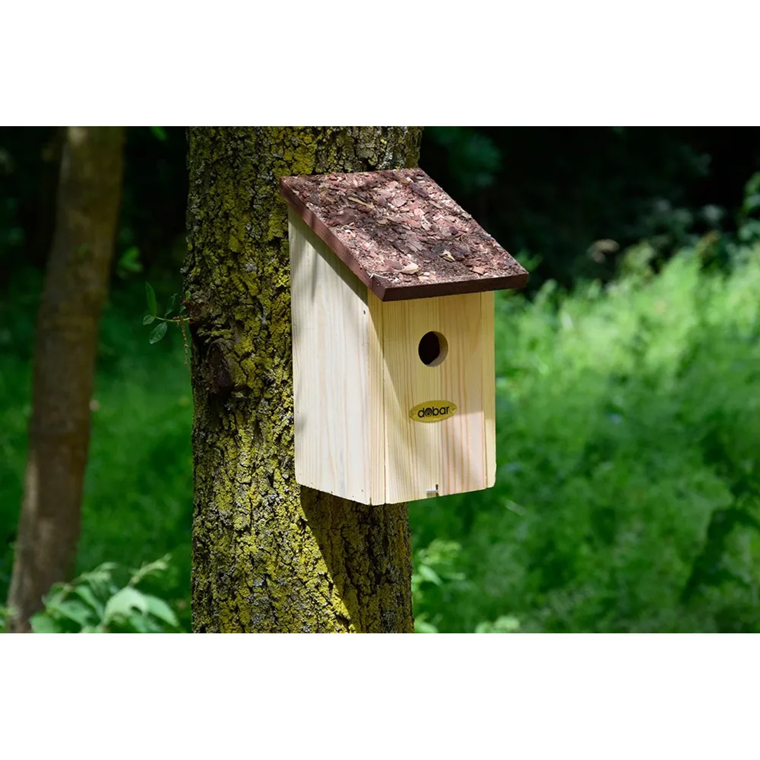 Nistkasten mit Rindendach aus Kiefernholz am Baum befestigt.
