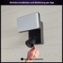 Schwarze Philips Hue Flutlichtkamera Secure mit Hand bei der Installation an einer Wand.
