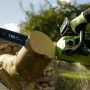 Greenworks Akku-Kettensäge GD40CS18 beim Sägen von Holz. Die Kettensäge ist grün und schwarz.