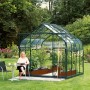 Vitavia Gewächshaus Diana 6700 ESG Smaragd Vorzugsset im Garten mit Frau am Tisch.