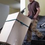 Mann transportiert Karton mit klappbarer wolfcraft Sackkarre TS 1500 auf Treppe.