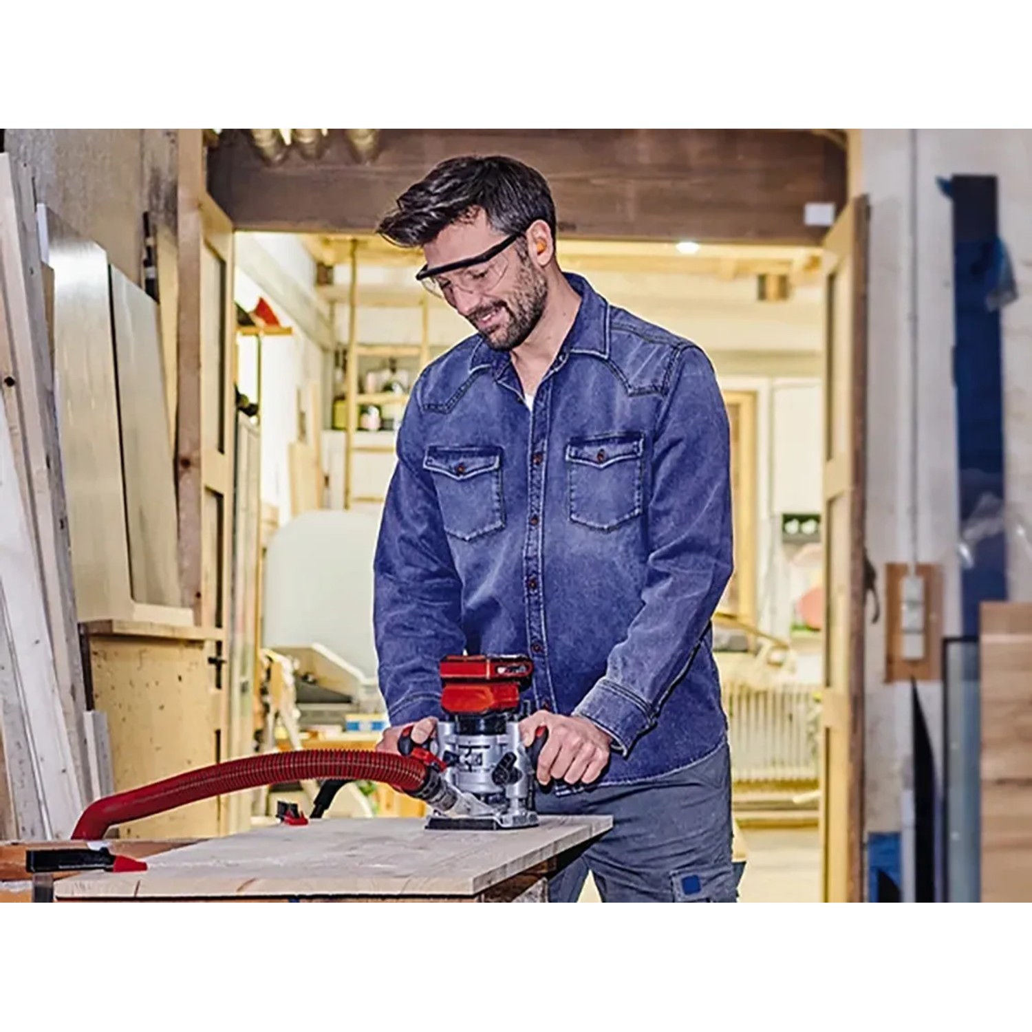 Mann arbeitet mit Einhell Akku-Oberfräse TP-RO 18 Li BL an Holz.