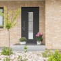Moderne, anthrazitfarbene Aluminium Sicherheitshaustür mit Glaselement und Edelstahlgriff am Hauseingang.