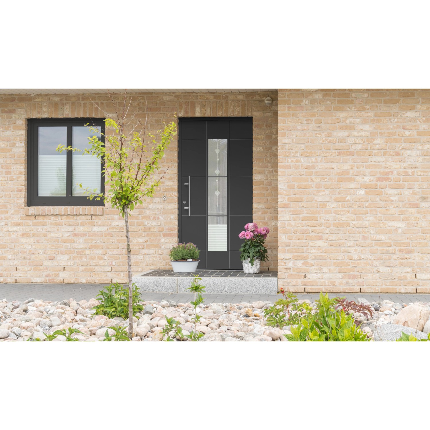 Moderne, anthrazitfarbene Aluminium Sicherheitshaustür mit Glaselement und Edelstahlgriff am Hauseingang.