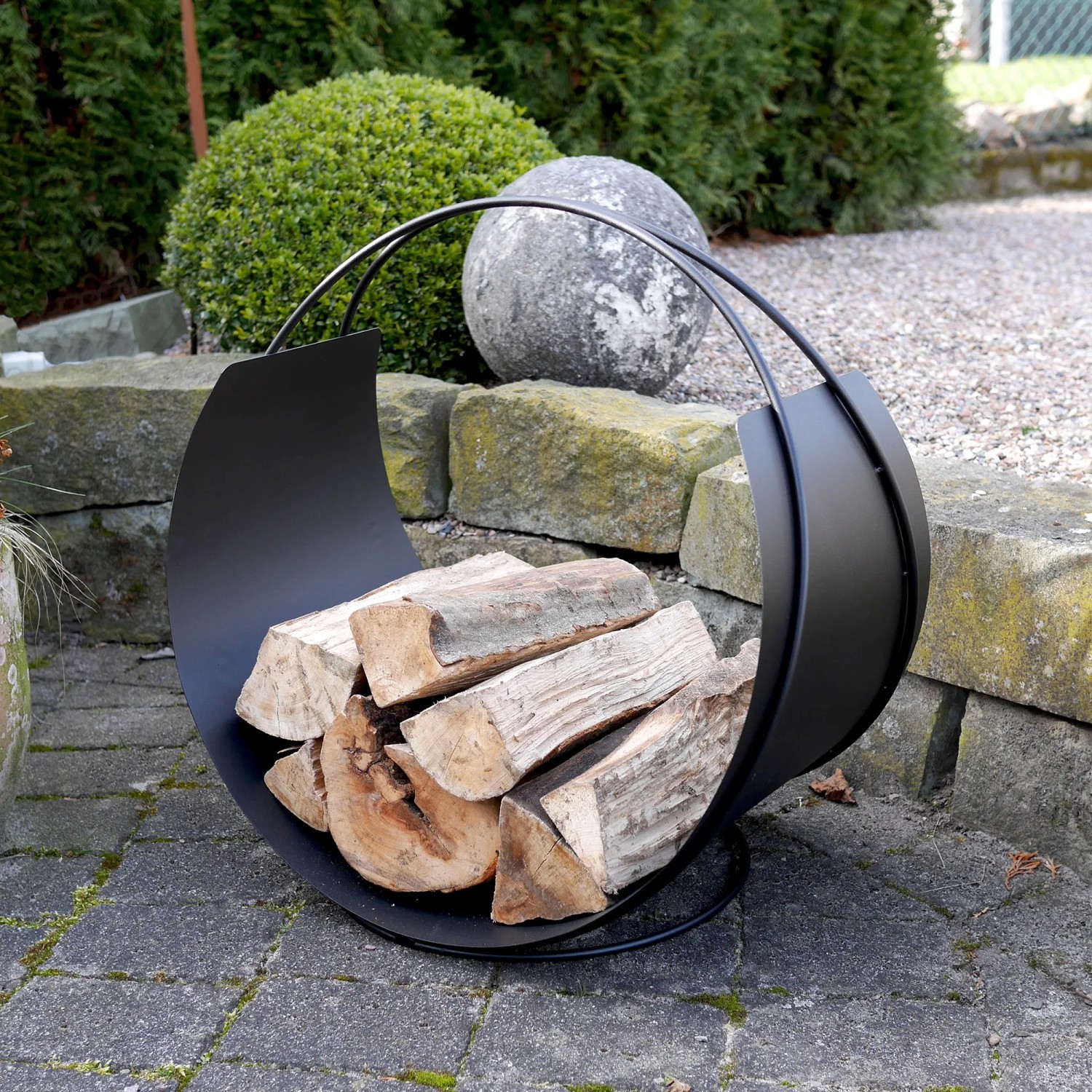 Schwarzer Vasner Kaminholzkorb Situro S1 aus Stahl, gefüllt mit Holzscheiten.