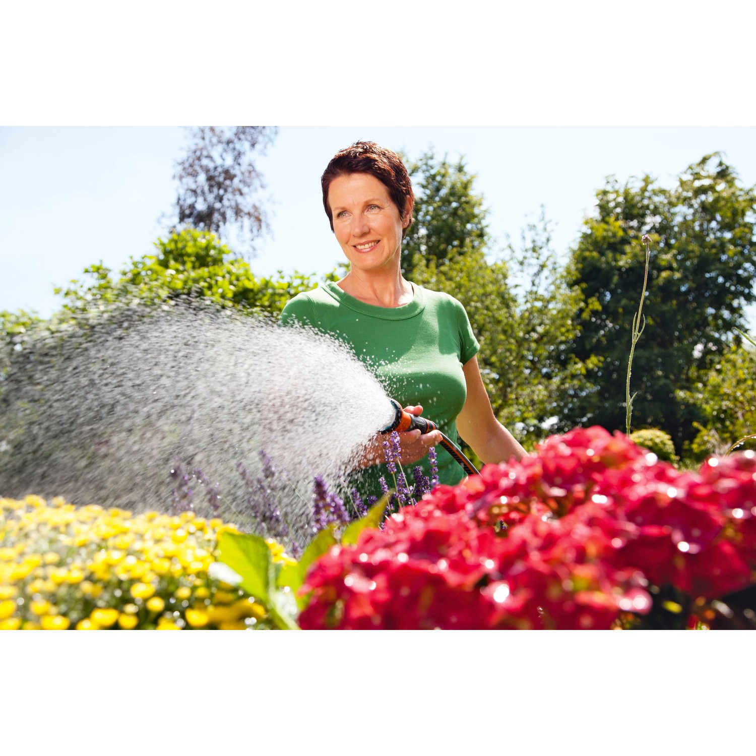 Frau bewässert Blumen mit Gardena Bewässerungsbrause. Gartenspritze mit regulierbarem Wasserstrahl.