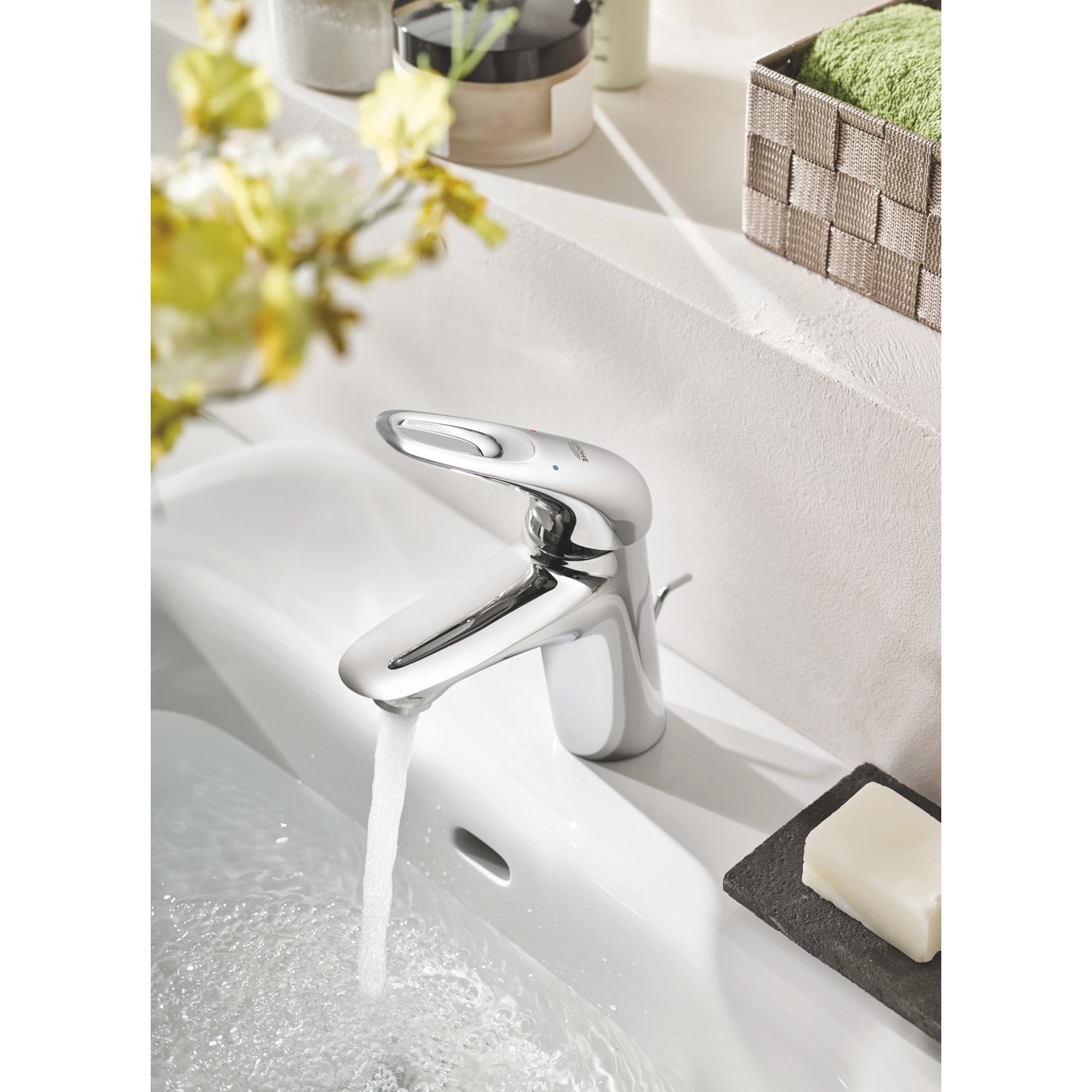 Glänzende Grohe Eurostyle Waschbeckenarmatur S-Size Chrom mit Wasserstrahl im weißen Waschbecken.