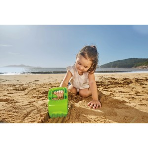 Kind spielt am Strand mit grünem Hape Sandspielzeug Handbagger.