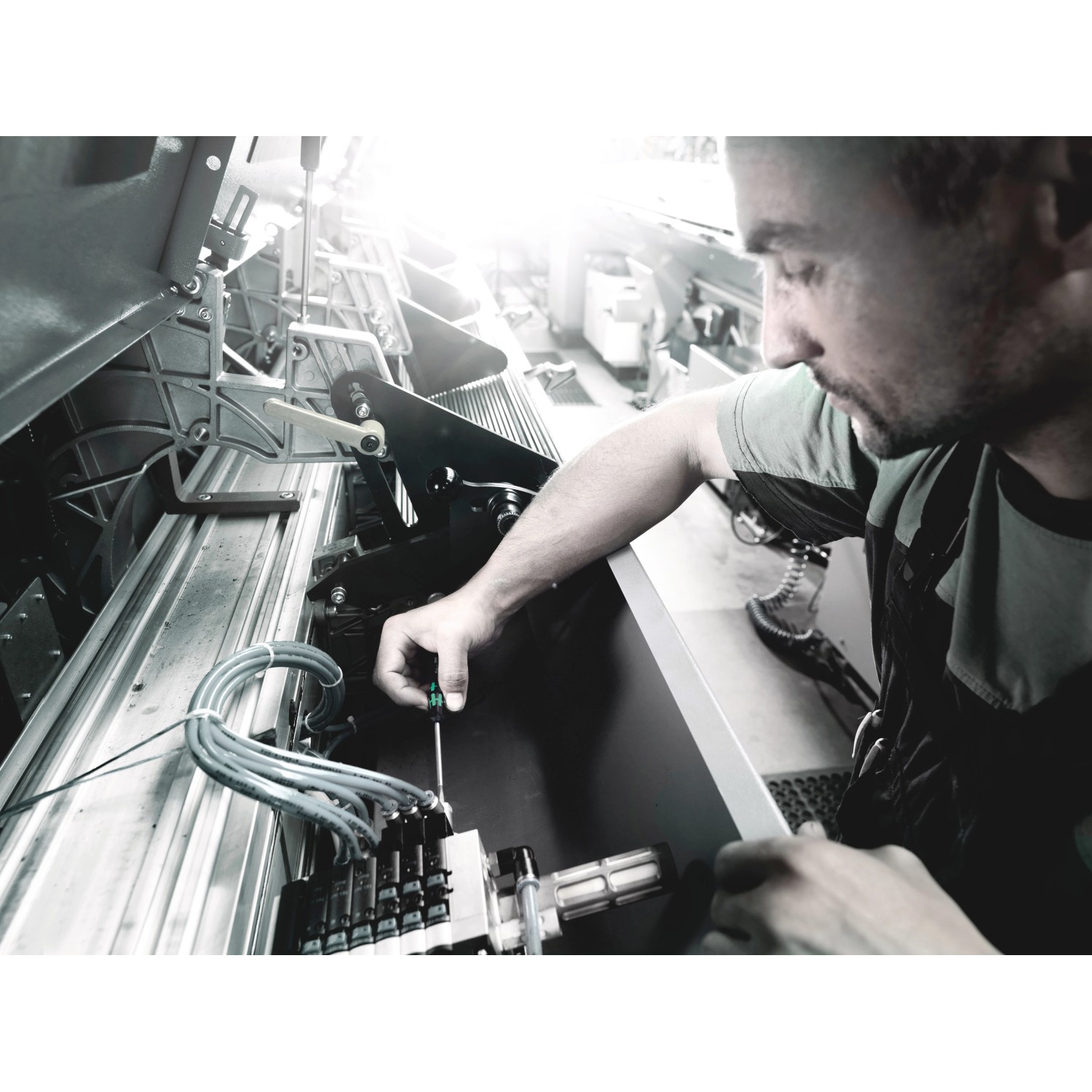 Mann arbeitet mit Wera TX-Schraubendreher an Maschine. Schraubenzieher für Elektronik und Feinmechanik.
