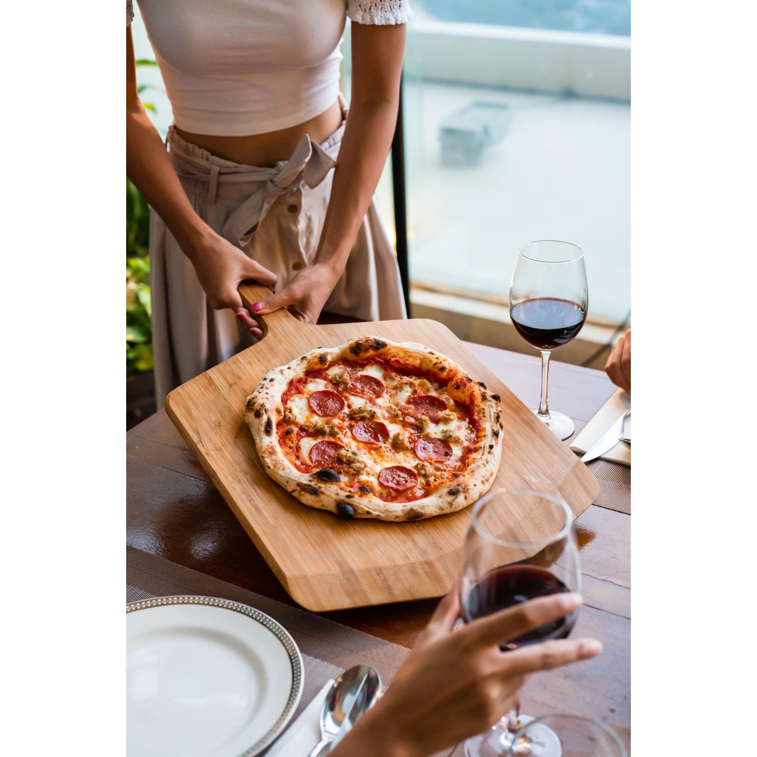 Ooni Pizzaschieber aus Bambus mit Pizza, auch als Servierbrett nutzbar.