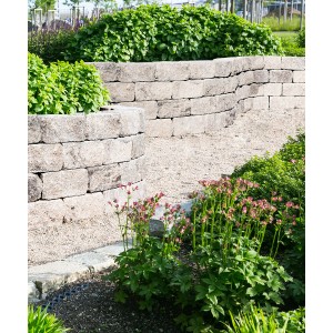 Mauer aus anthrazit-schattierten Trapez Mauersteinen als Beetbegrenzung im Garten.