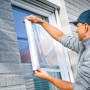 Mann bringt LUX Fensterschutzfolie am Fenster an. Klebefolie schützt vor Schmutz bei Renovierung.