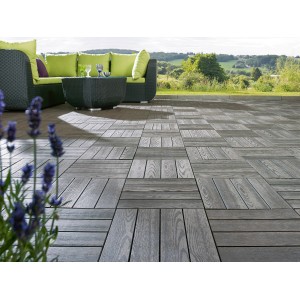 Verlegte, anthrazitfarbene WPC Klickfliesen in Holzoptik auf einer Terrasse mit Gartenmöbeln.