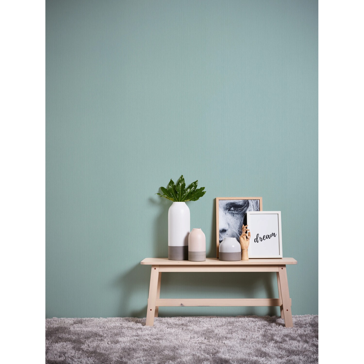 Michalsky Living Vliestapete Uni Blau an Wand, kombiniert mit Deko-Elementen auf einer Holzbank.