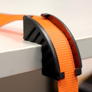 Detailaufnahme: Oranger Las Spanngurt mit Ratsche und schwarzem Kantenschutz.