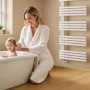 Weißer Emke Handtuchheizkörper im Bad, Frau badet Kind. Heizkörper für warme Handtücher und angenehme Wärme.