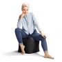 Frau sitzt auf schwarzem Sitting Point Hocker (60 l). Bequemer Sitzsack für Indoor & Outdoor.