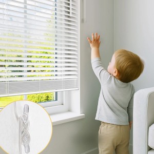 Weiße Sol Royal Alu Jalousie am Fenster, Kind greift daneben. Detailansicht des Kindersicherungsclips für Zugschnüre.