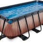 Rechteckiger EXIT Wood Pool in Braun mit Stahlrahmen und Filterpumpe, gefüllt mit Wasser.
