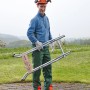 Mann trägt zusammengeklappten wolfcraft Sägebock SB 60. Klappbarer Arbeitsbock für Holz.