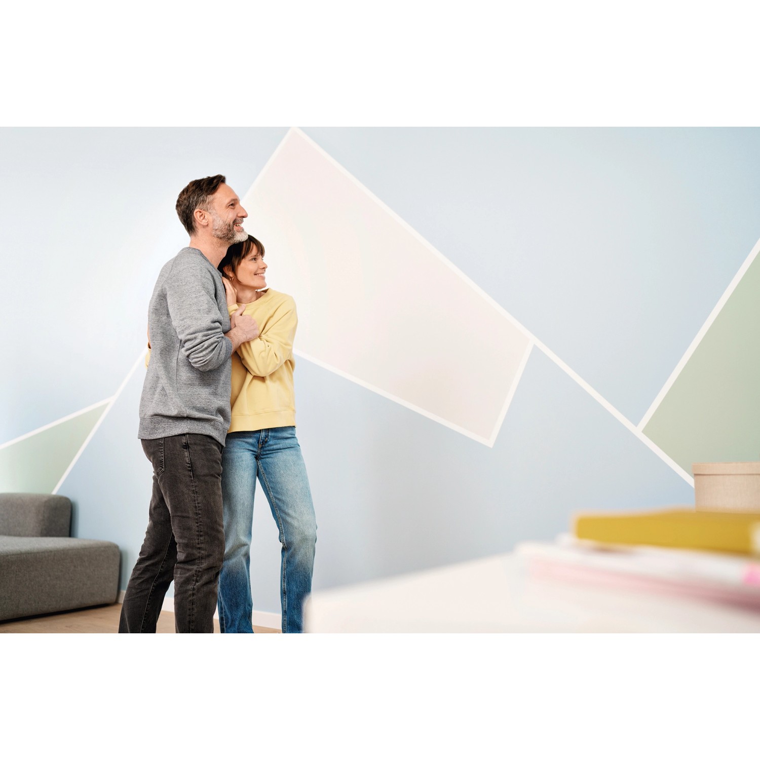 Paar betrachtet Wand mit präzisen Farbkanten, abgeklebt mit Tesa Malerband Professional.