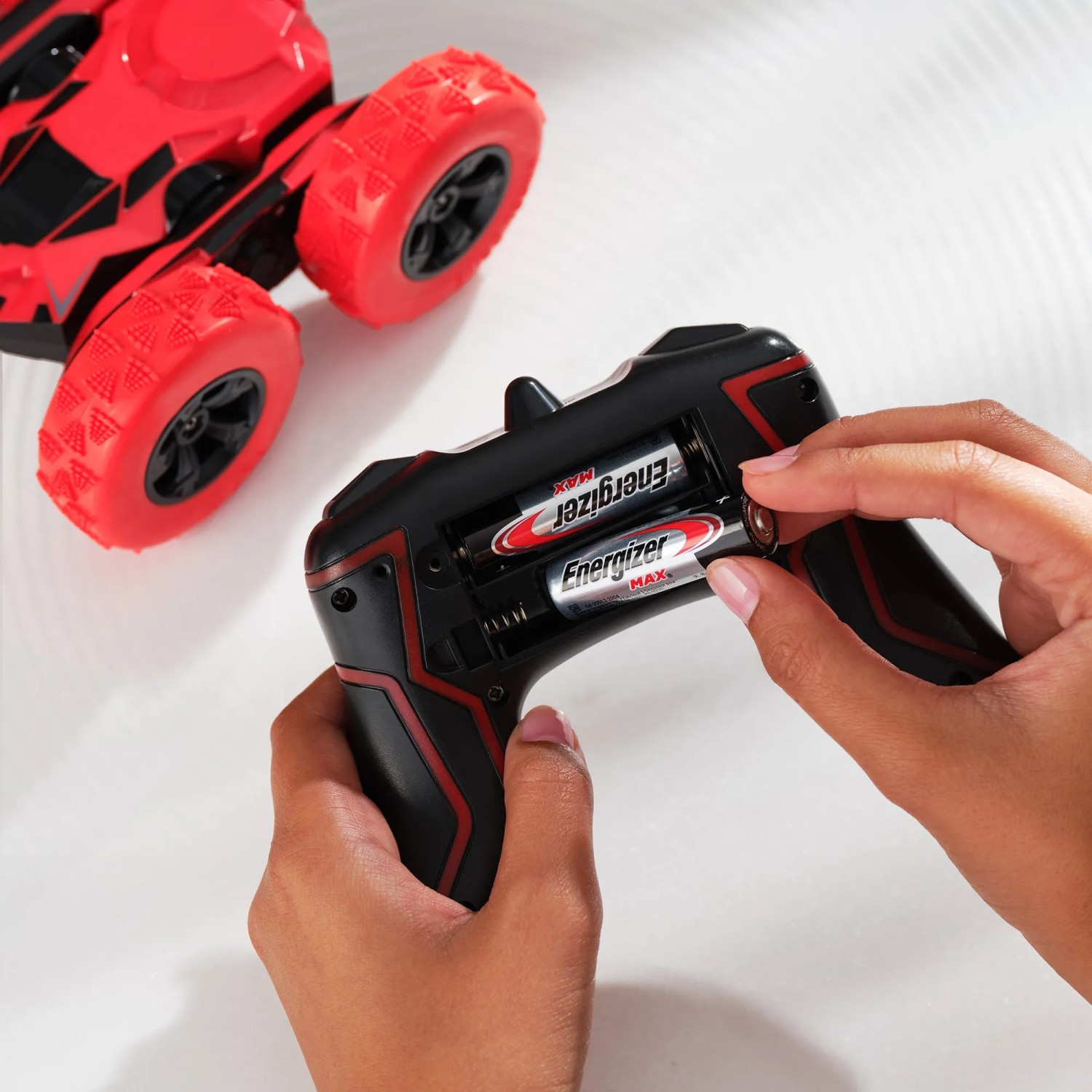 Einsetzen von Energizer Max AA Batterien in eine Fernbedienung, mit Spielzeugauto im Hintergrund.