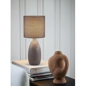 Graue PR Home Uno Tischleuchte mit geripptem Keramikfuß und Stoffschirm auf Büchern. Skandinavisches Design für Innenleuchten.