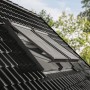 Elektrischer Alu-Rollladen CK04 für Dachfenster, teilweise geöffnet, montiert auf einem dunklen Ziegeldach.