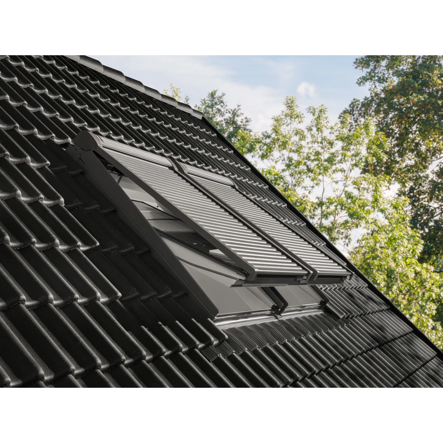 Elektrischer Alu-Rollladen CK04 für Dachfenster, teilweise geöffnet, montiert auf einem dunklen Ziegeldach.
