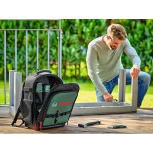 Offener Bosch Werkzeug-Rucksack mit 60 Handwerkzeugen. Mann montiert Möbel im Garten. Robustes DIY-Set.