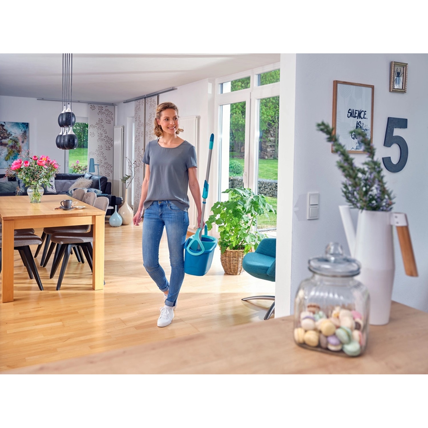 Frau mit Leifheit Clean Twist Disc Mop Ergo Reinigungsset und Eimer zur Bodenreinigung.