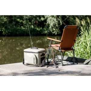Petromax Kühltasche 22L mit Kühlakku, grau-schwarz, neben Angelstuhl und Kescher.