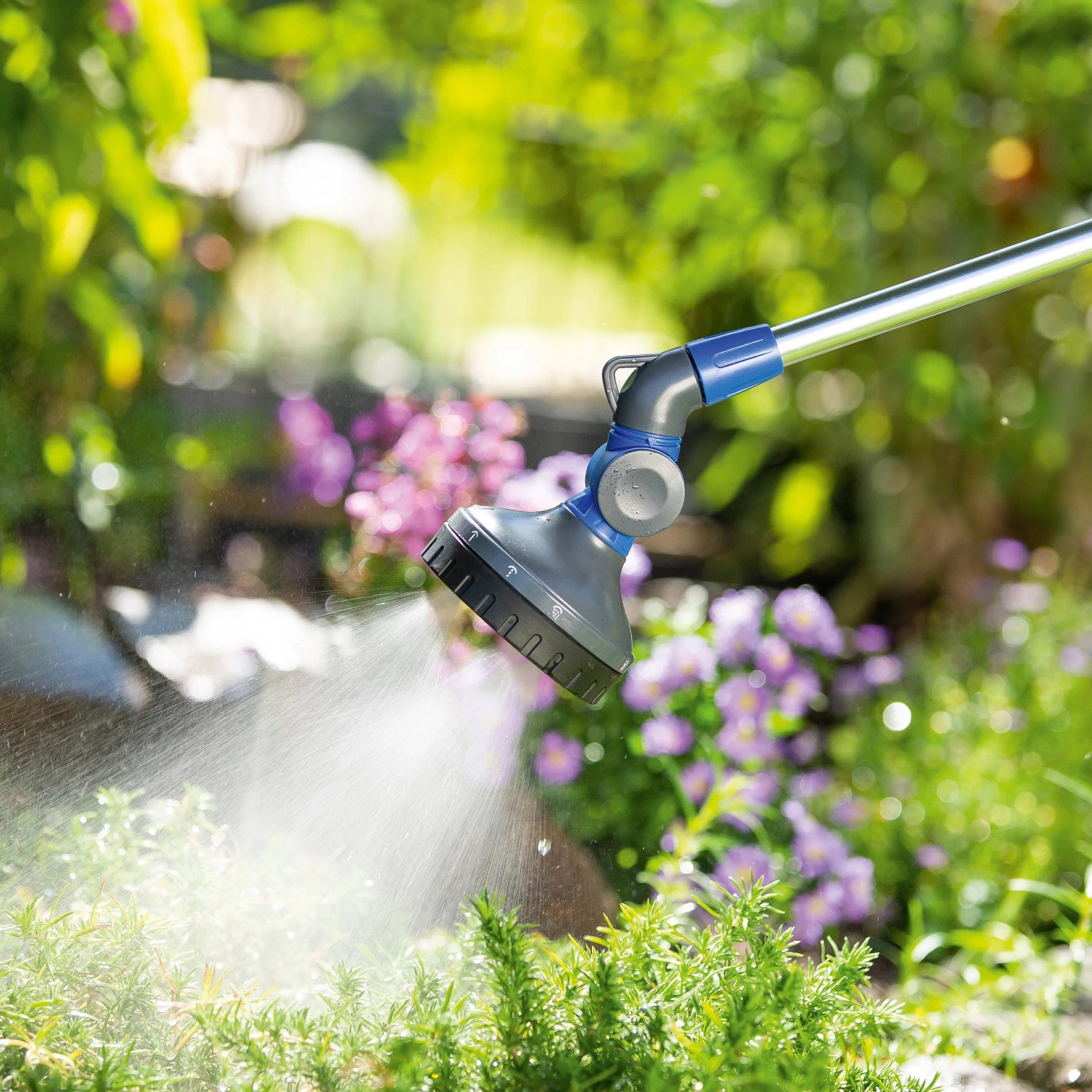 LUX Gießstab mit 10 Strahlvarianten beim Bewässern von Pflanzen im Garten.