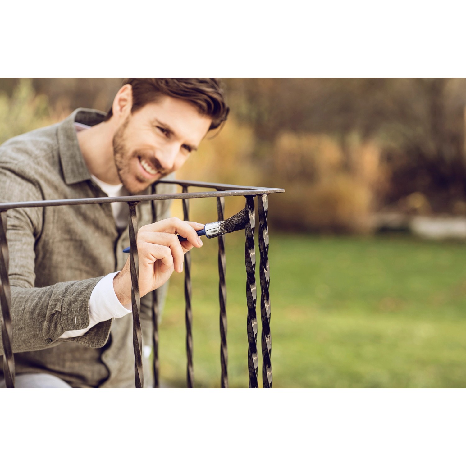 Mann streicht Metallgeländer mit Hammerite Ultima Metallschutzlack Verkehrsgrau.