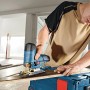 Mann schneidet Holz mit blauer Bosch Professional Akku-Stichsäge GST 12 V-70. Präzises Sägen auf Baustelle.