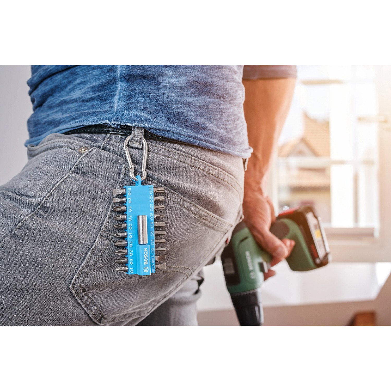 Bosch Schrauberbit-Set, 21-teilig, mit Snap-Hook am Gürtel, Schrauber in Hand.