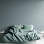 Schlafzimmer mit blauer AS-Creation Vliestapete Uni Struktur und Bett mit passender Bettwäsche.