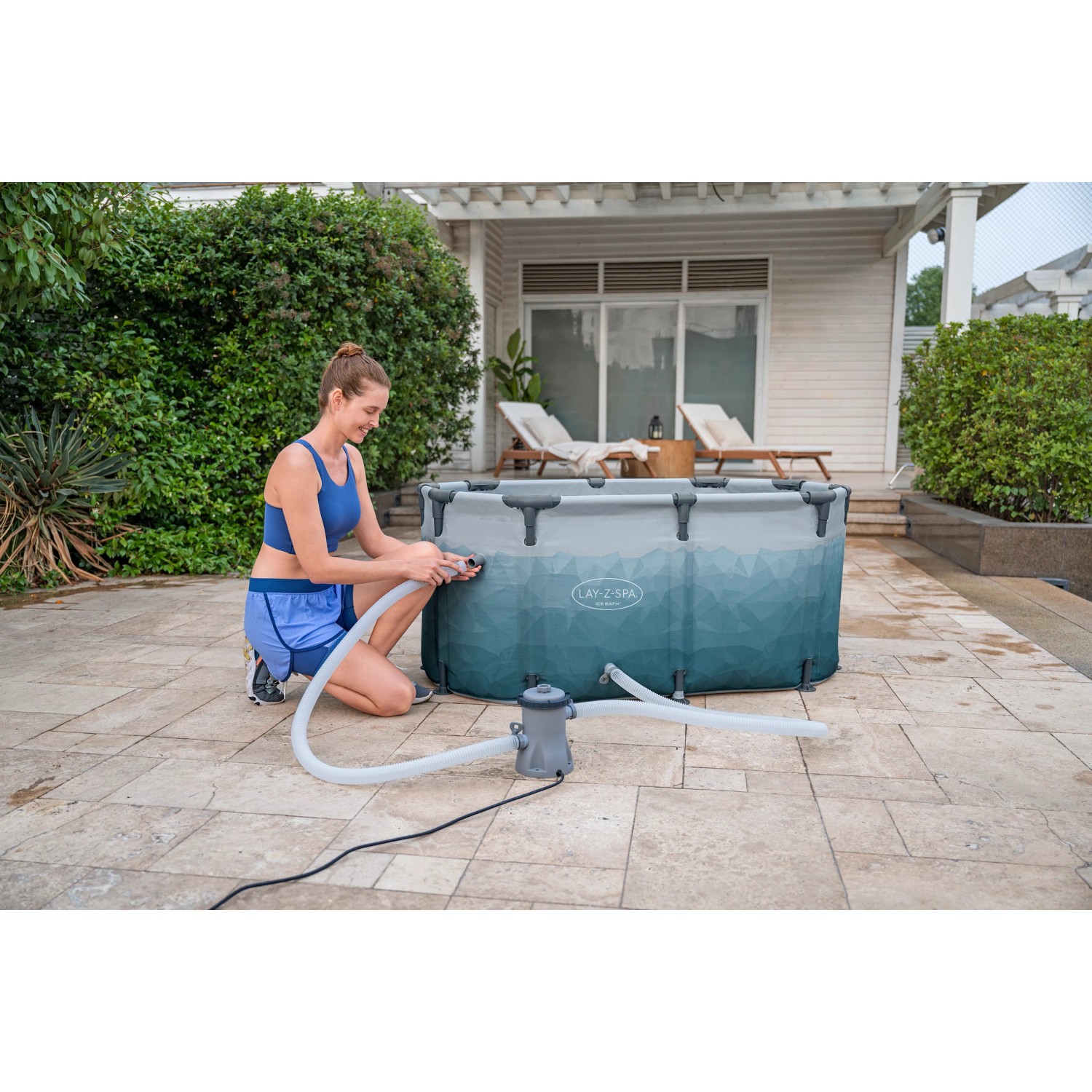 Bestway Eisbad Glacial Dip mit Filterpumpe, aufgebaut im Garten. Frau schließt Pumpe an.
