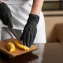 Schwarze Einmalhandschuhe (latexfrei, Gr. S) beim Schneiden von Käse.