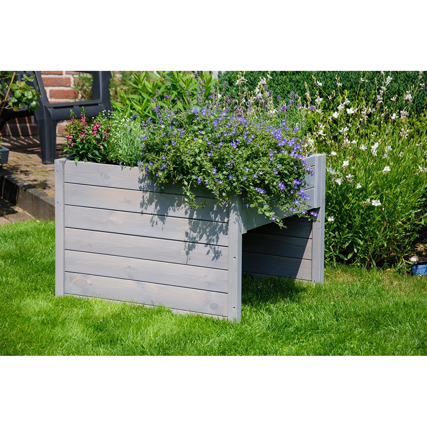 Graue Dobar Mährobotergarage mit Pflanzkasten, bepflanzt mit Blumen, im Garten.